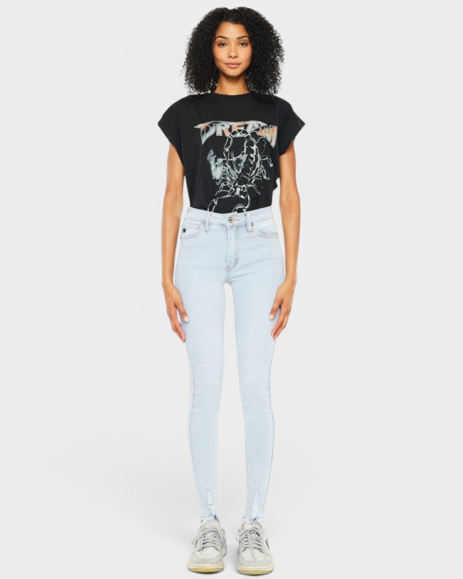 Woman wearing a black t-shirt with graphic design and light blue jeans on a white background