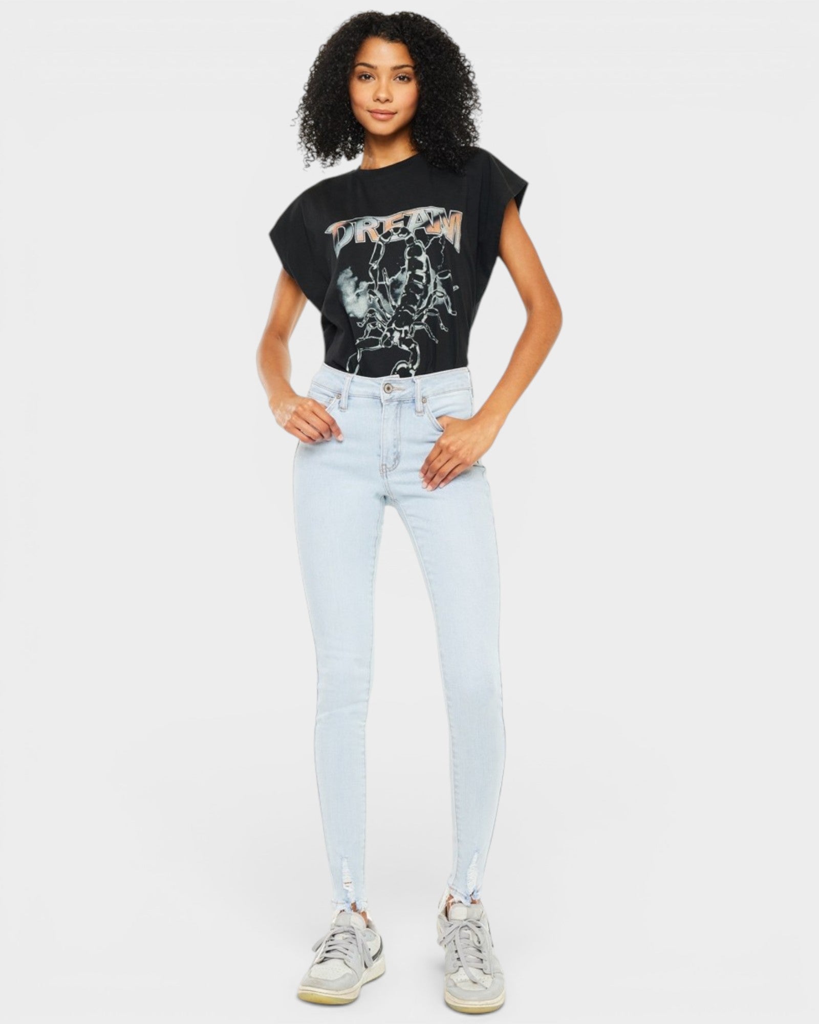 Person wearing a black t-shirt with graphic design and light blue jeans on a white background