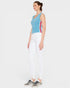 Woman wearing a blue sleeveless top with red and white stripes and white pants on a light gray background