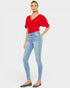 Woman wearing a red top and light blue jeans on a white background
