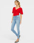 Woman wearing a red top and light blue jeans on a white background