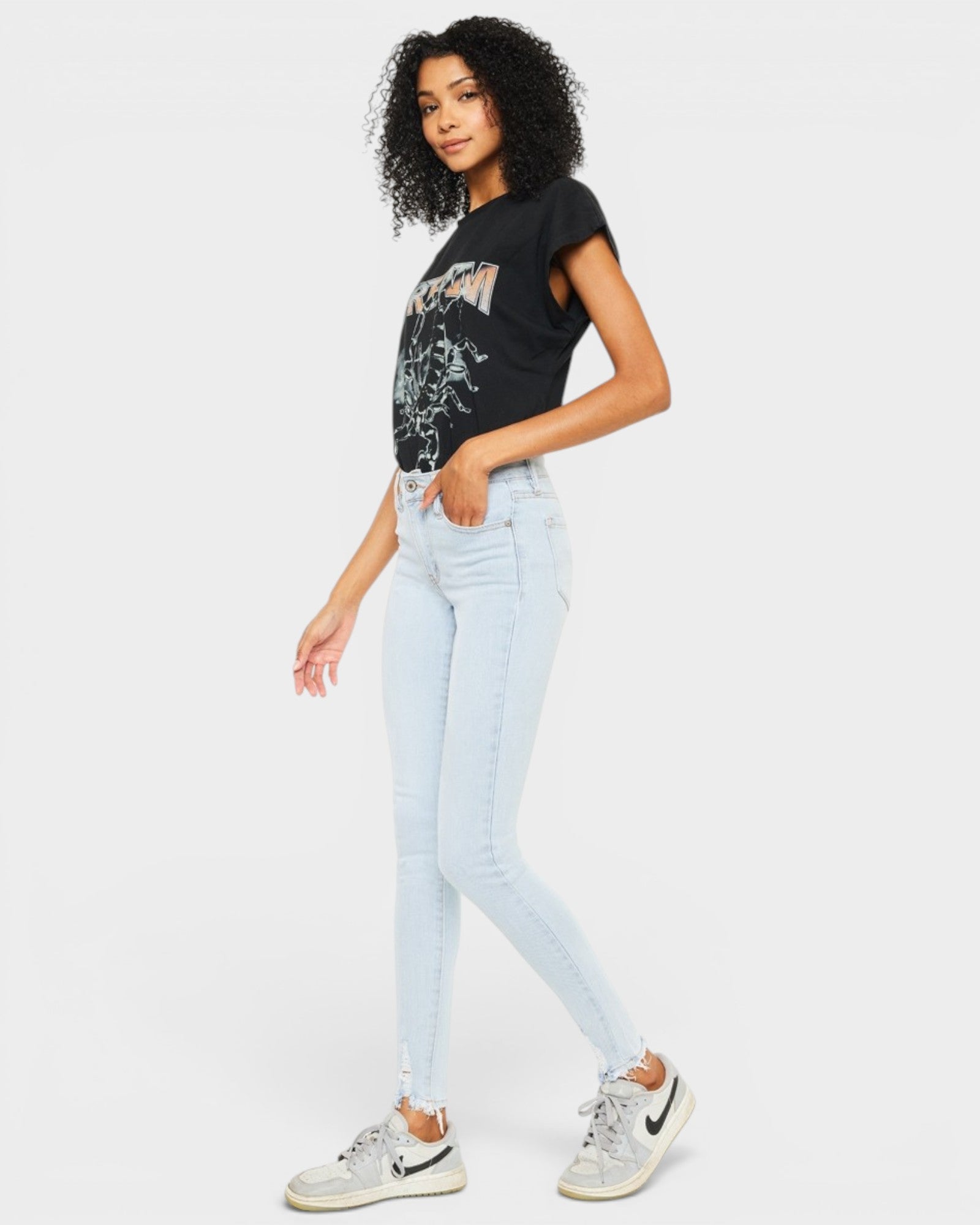 Woman wearing a black t-shirt with a graphic design and light blue jeans on a white background
