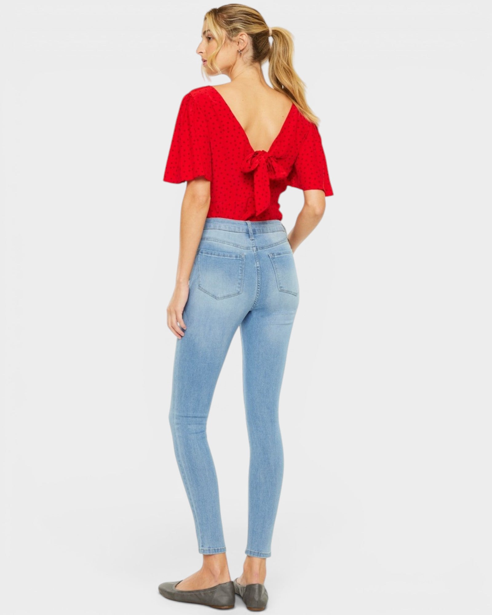 Woman wearing a red blouse and light blue jeans on a white background