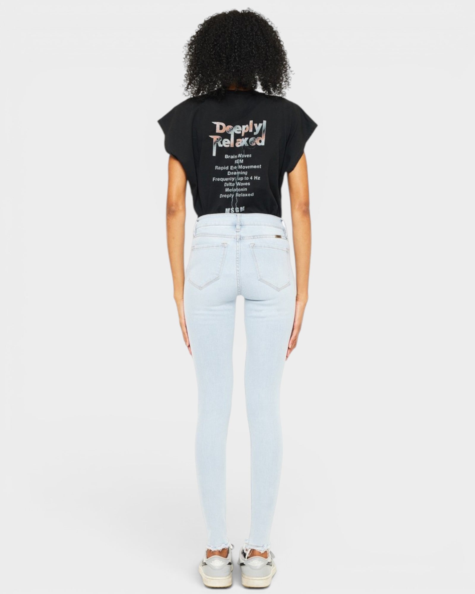 Person wearing a black t-shirt with text and light blue jeans on a white background