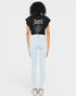 Person wearing a black t-shirt with text and light blue jeans on a white background