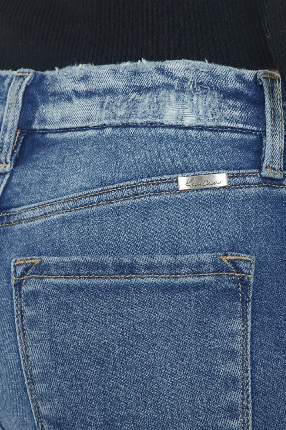 Close-up of blue jeans with a brand label on the back pocket.
