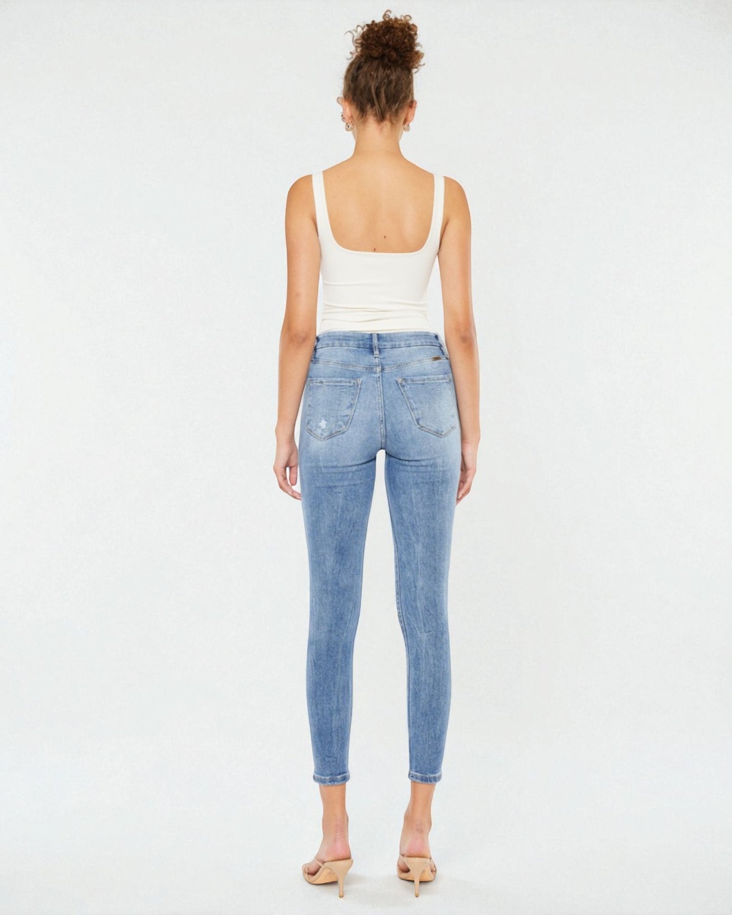 Woman wearing light blue jeans and a white top on a white background