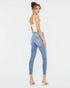 Woman wearing light blue jeans and a white top on a white background