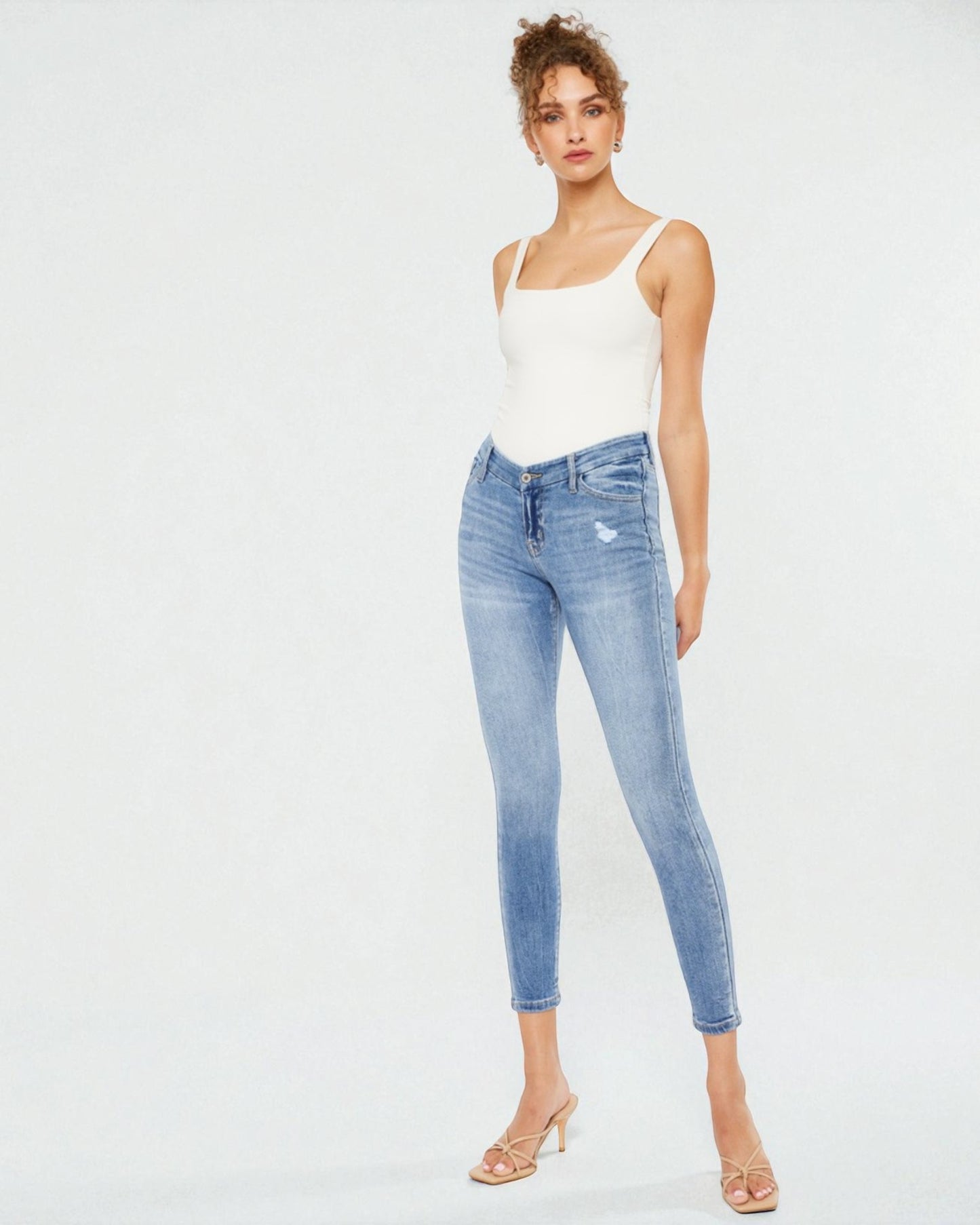 Woman wearing light blue jeans and a white top on a white background
