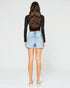 Person wearing a black long-sleeve top and light blue denim shorts on a white background