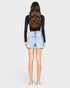 Person wearing a black long-sleeve top and light blue denim shorts on a white background