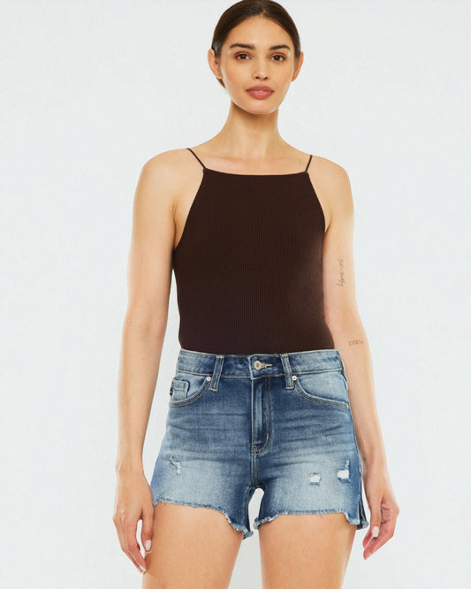 Woman wearing a black tank top and denim shorts on a white background