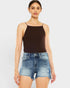 Woman wearing a black tank top and denim shorts on a white background