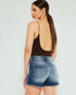 Woman wearing a brown open-back top and denim shorts on a white background