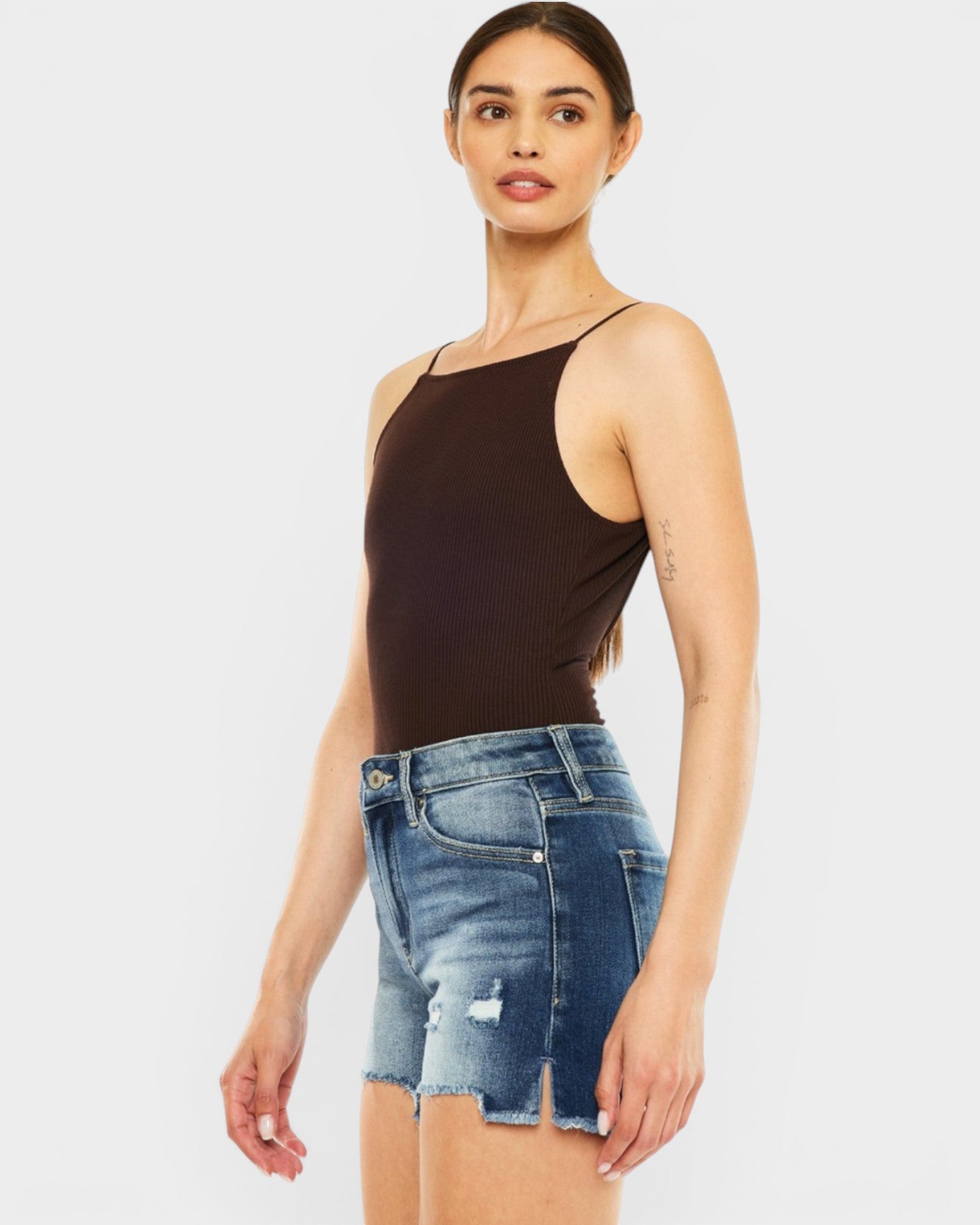 Woman wearing a black tank top and denim shorts on a white background
