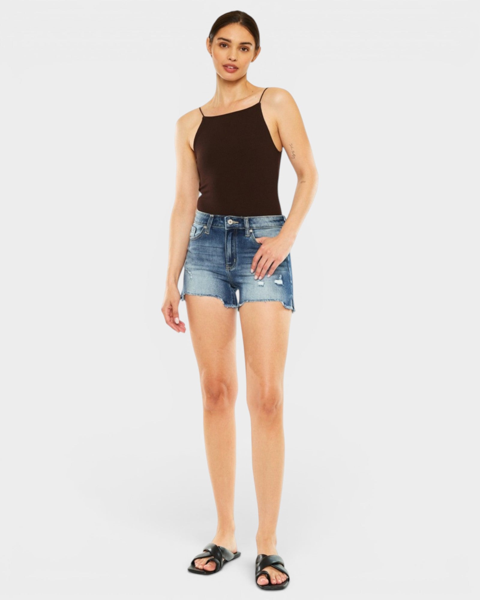 Woman wearing a black tank top and denim shorts on a white background