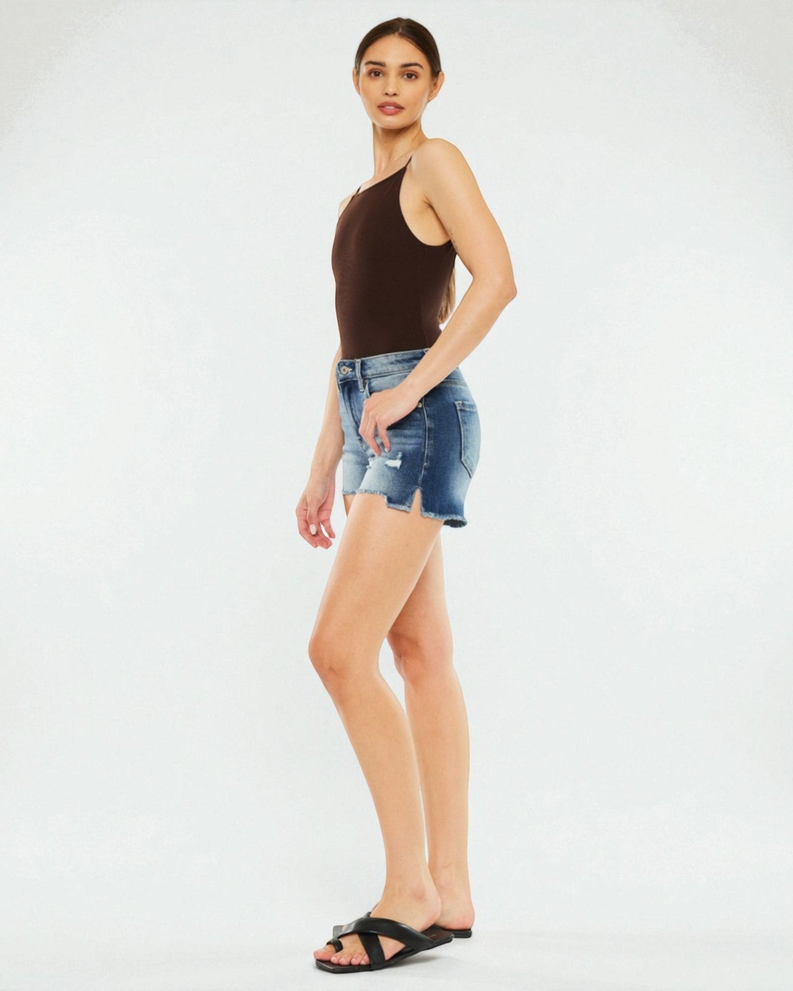 Woman wearing a brown top and denim shorts on a white background