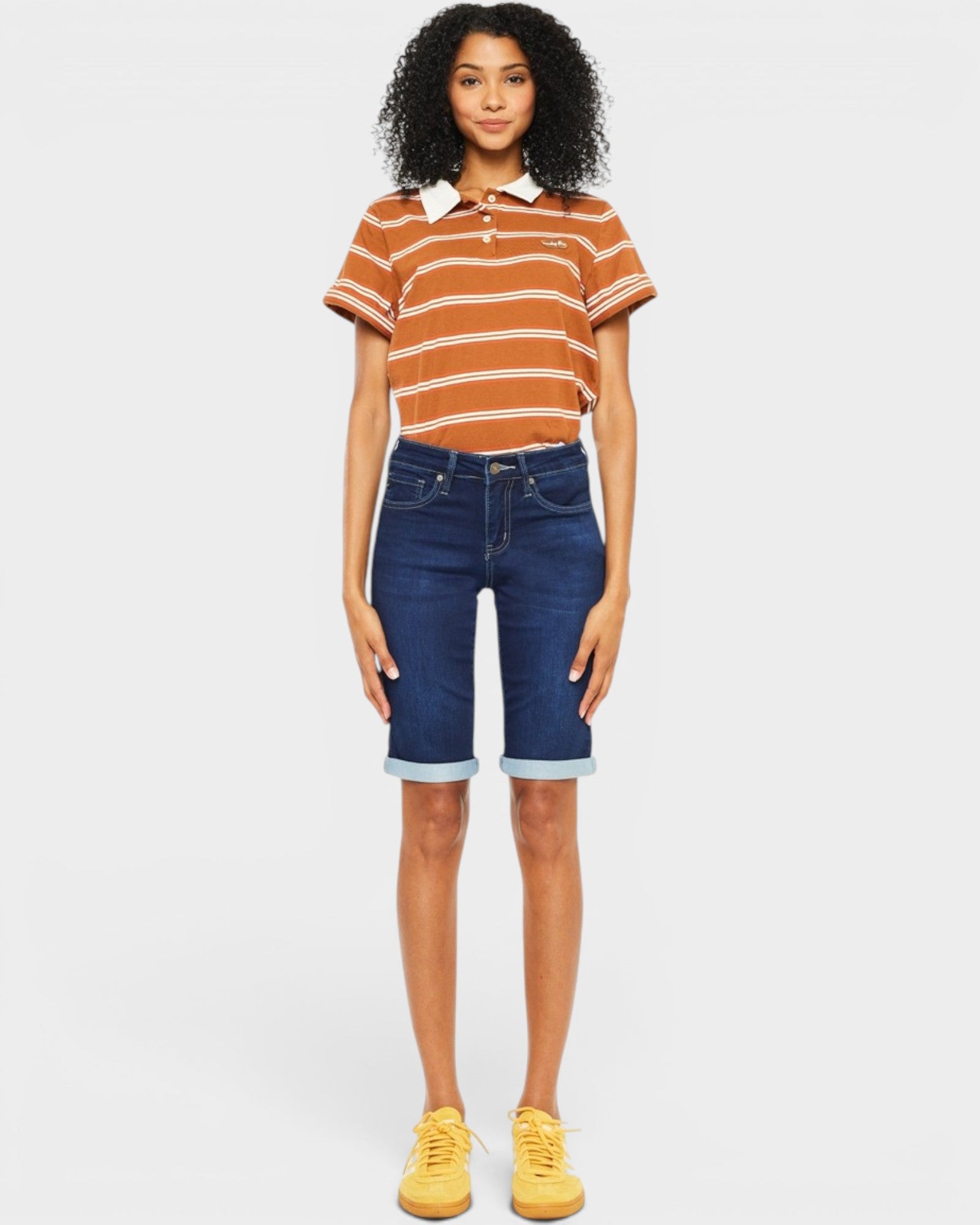 Person wearing a striped shirt and denim shorts on a plain background