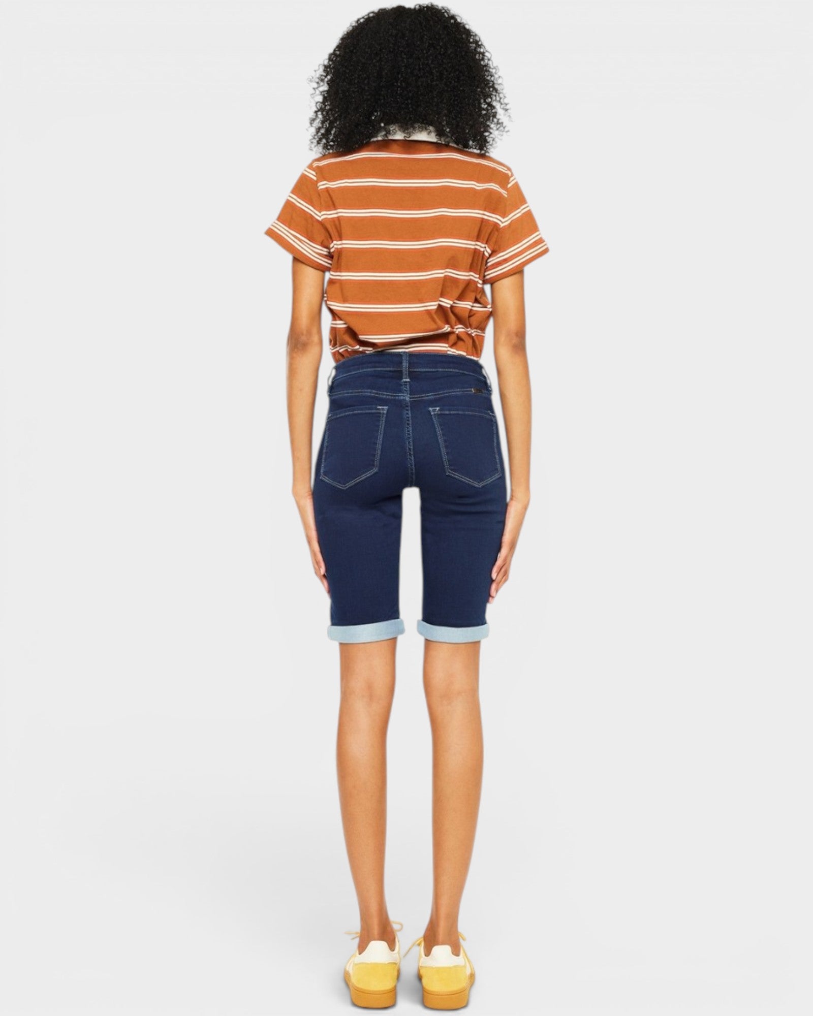 Person wearing a striped shirt and denim shorts on a white background