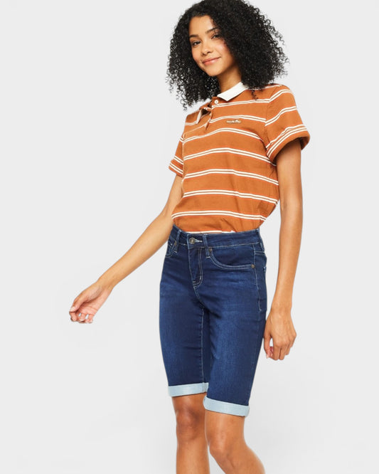 Woman wearing a striped polo shirt and blue shorts on a white background