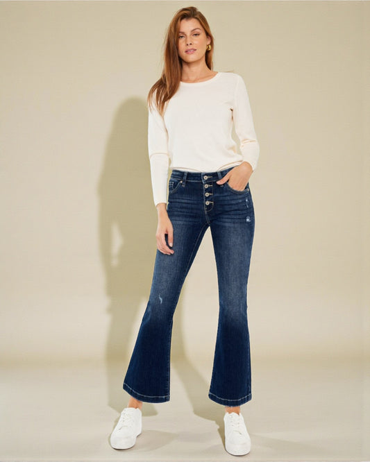 Woman wearing a white sweater and blue jeans on a beige background