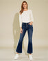 Woman wearing a white sweater and blue jeans on a beige background
