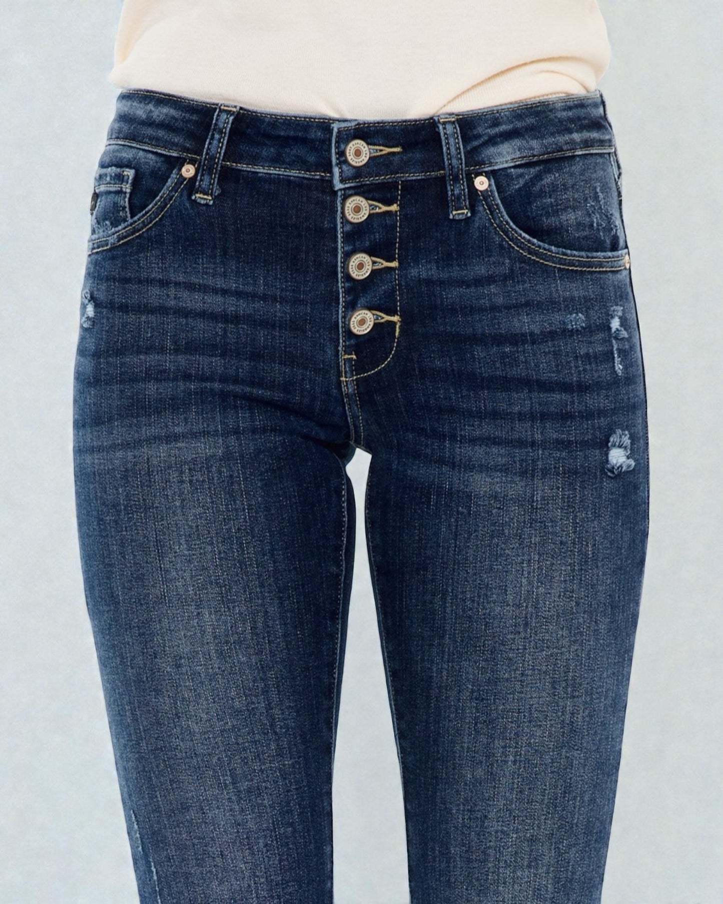 Blue jeans with button details on a light gray background