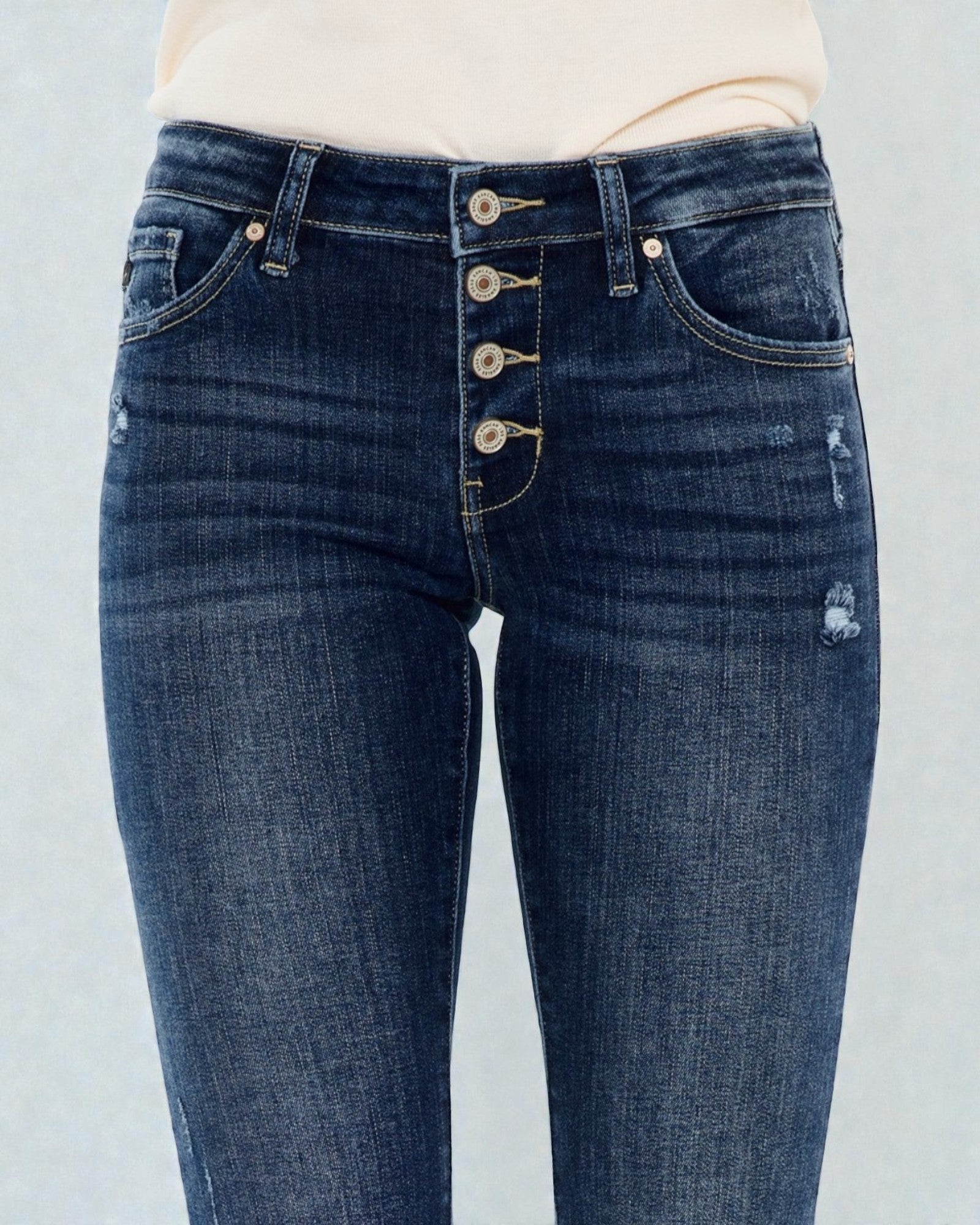 Blue jeans with button details on a light gray background