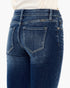 Close-up back view of a person wearing dark blue denim jeans with a cream top, showing the back pockets and waistband details.
