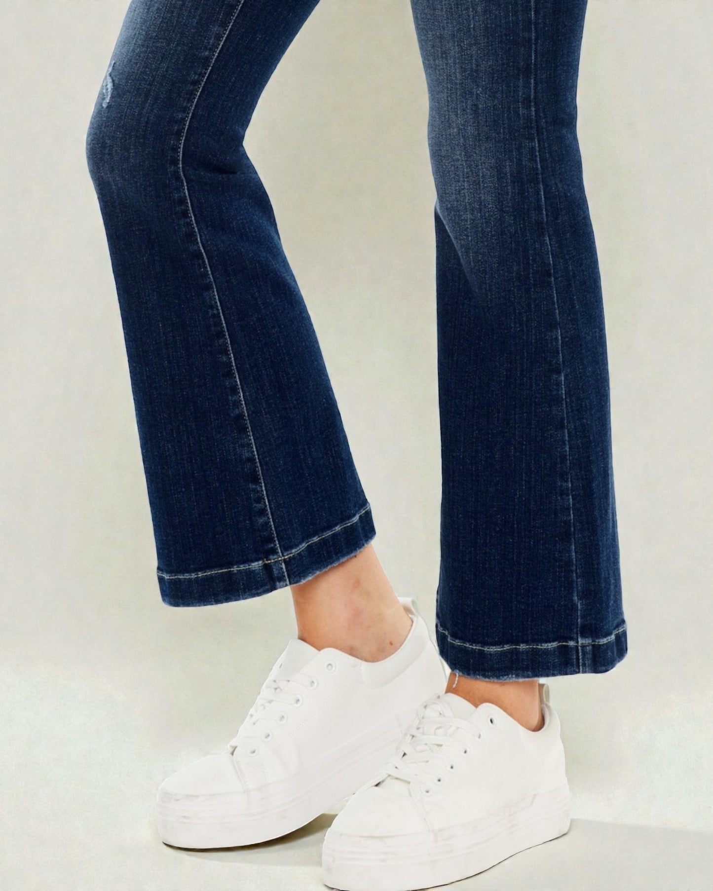Dark blue jeans with white sneakers on a light gray background