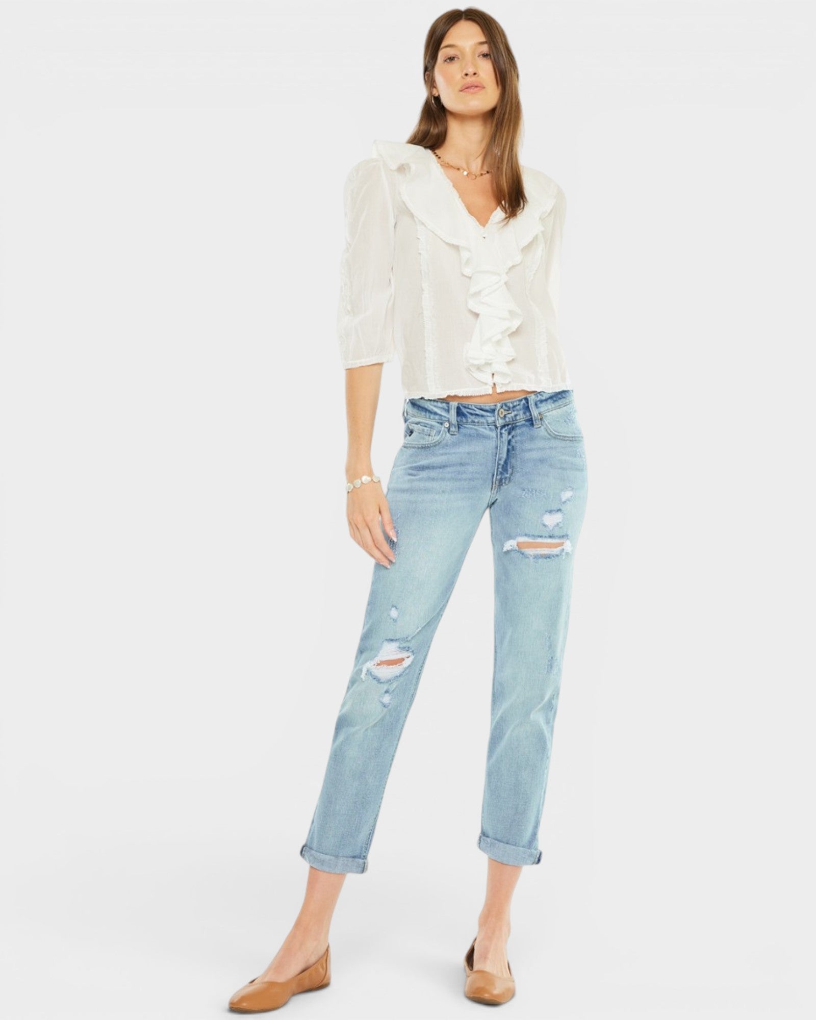 Woman wearing a white blouse and light blue jeans on a white background
