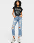 Person wearing a black t-shirt with graphic design and light blue ripped jeans on a white background
