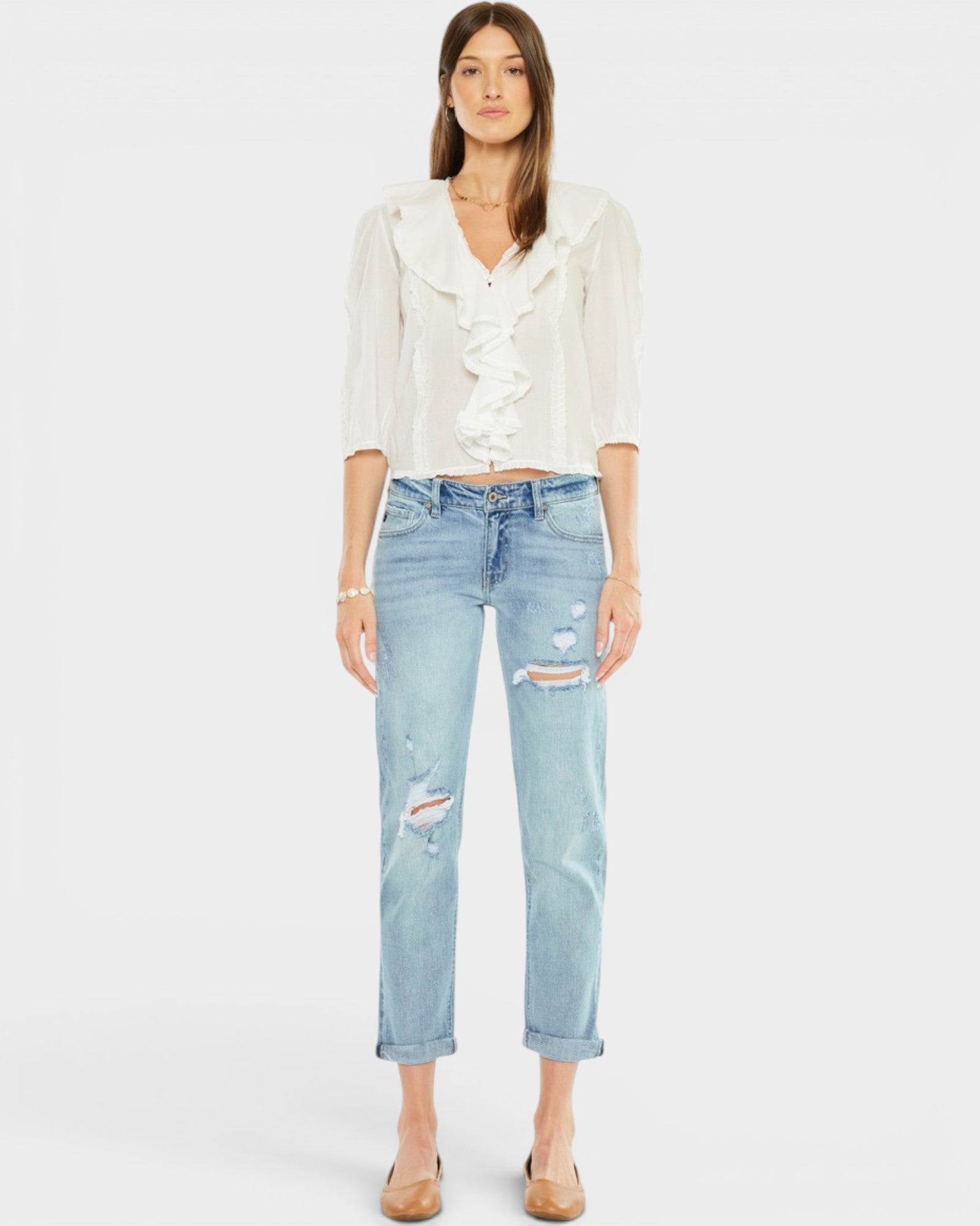 Woman wearing a white blouse and light blue jeans on a plain background