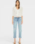 Woman wearing a white blouse and light blue jeans on a plain background