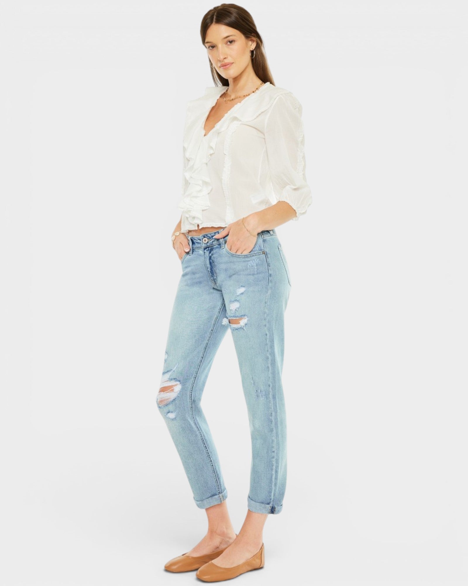 Woman wearing a white blouse and light blue jeans on a white background