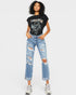Woman wearing a black graphic t-shirt and blue distressed jeans on a white background