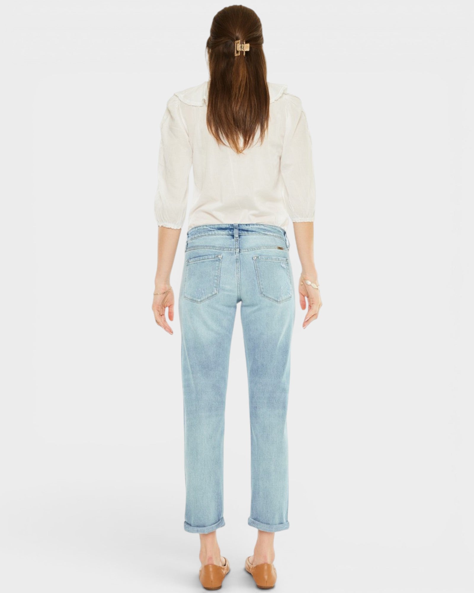 Woman wearing light blue jeans and a white blouse on a plain background