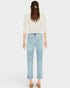Woman wearing light blue jeans and a white blouse on a plain background
