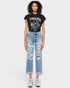 Person wearing a black t-shirt with graphic design and ripped blue jeans on a white background