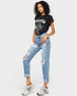 Woman wearing a black graphic t-shirt and light blue ripped jeans on a white background