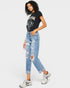 Woman wearing a black graphic t-shirt and light blue ripped jeans on a white background
