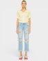 Person wearing a yellow top and light blue ripped jeans on a white background