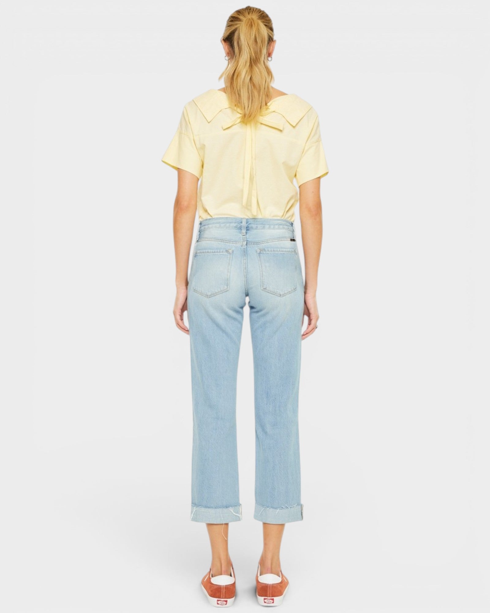 Person wearing a yellow shirt and light blue jeans on a white background