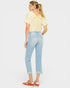Woman wearing a yellow top and light blue jeans on a white background