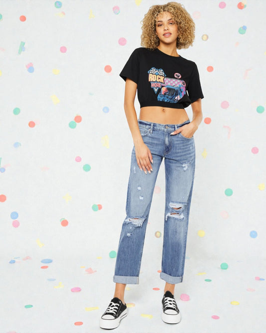 Woman wearing a black graphic t-shirt and blue jeans on a polka dot background