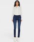 Woman wearing a white blouse with black patterns and blue jeans on a white background