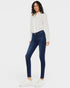 Woman wearing a white blouse with black patterns and dark blue jeans on a white background