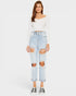 Woman wearing a white long-sleeve top and light blue ripped jeans on a white background