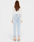 Person wearing light blue jeans and a white top on a plain background