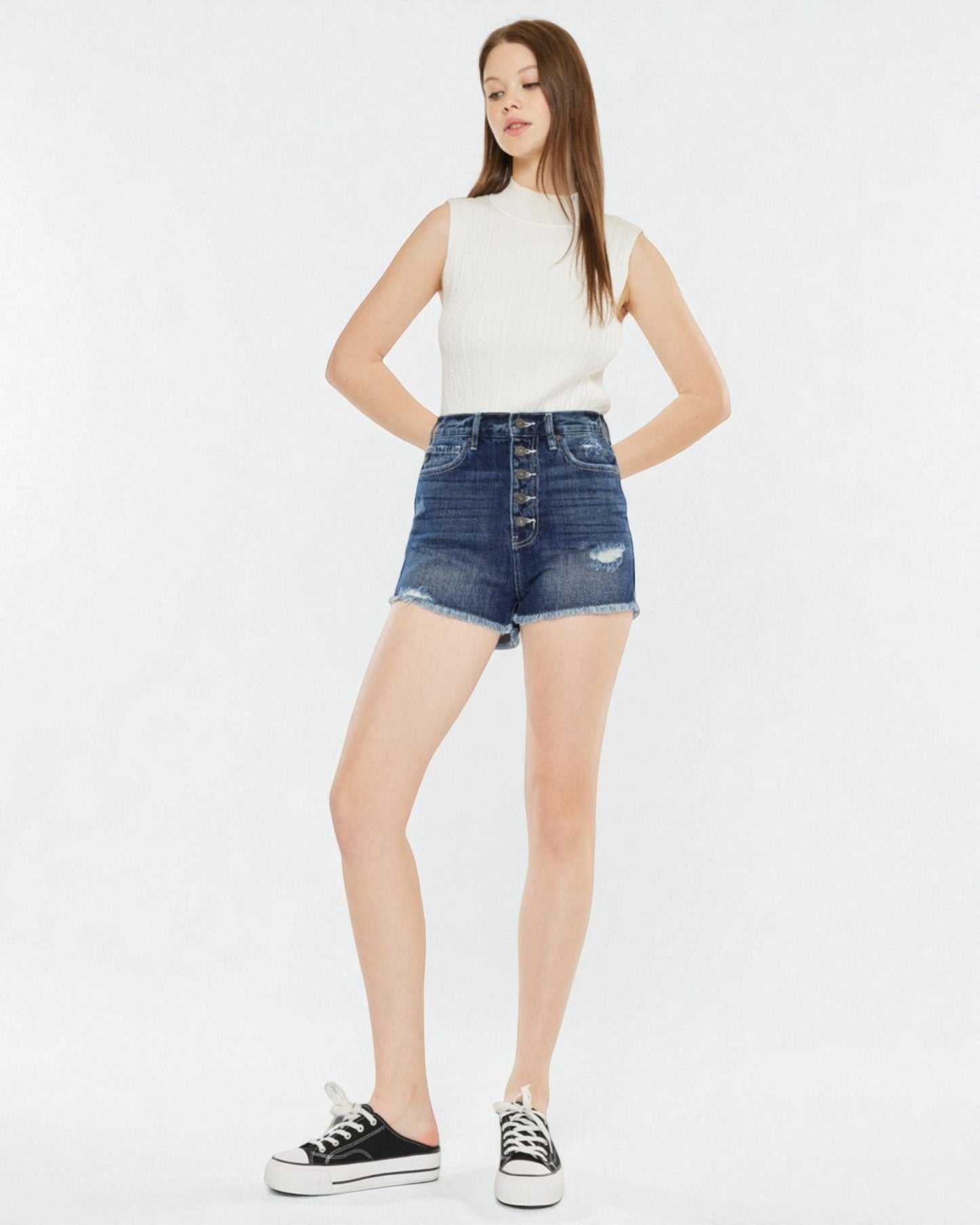 Woman wearing a white sleeveless top and denim skirt on a white background